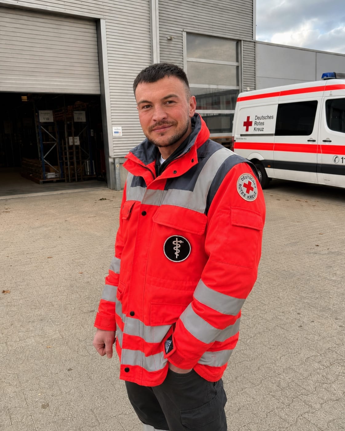 Tedd Schreiner wearing German Red Cross gear in front of an emergency vehicle